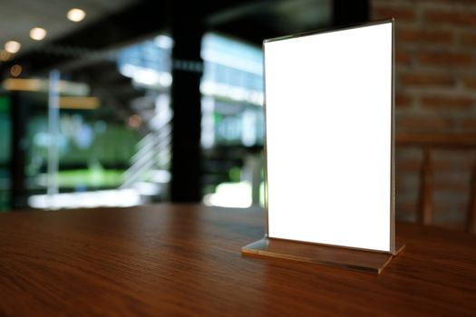 Mock up Menu frame standing on wood table in Bar restaurant cafe. space for text