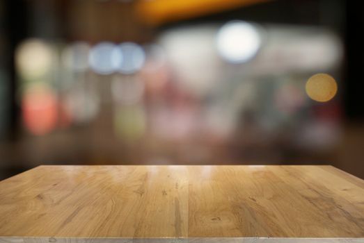 Empty dark wooden table in front of abstract blurred background of cafe and coffee shop interior. can be used for display or montage your products