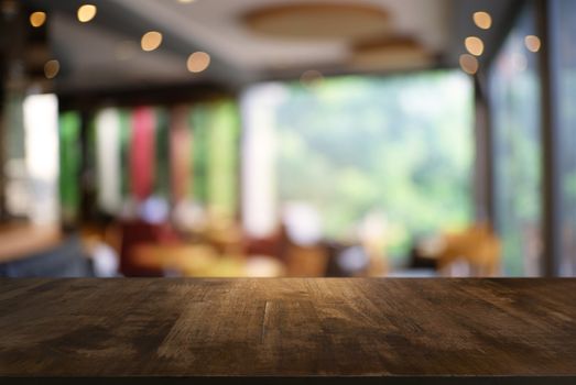 Empty dark wooden table in front of abstract blurred background of coffee shop . can be used for display or montage your products.Mock up for display of product.