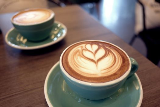 Cup of hot latte art coffee on wooden table