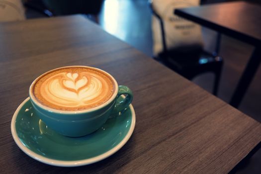 Cup of hot latte art coffee on wooden table