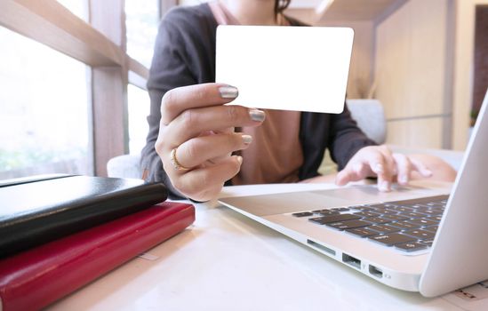 Young woman hands holding plastic credit card and using laptop. Online shopping concept