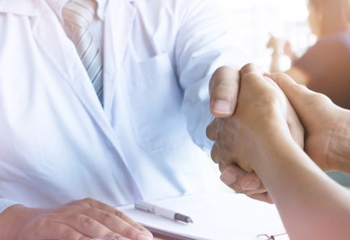 Doctor holding patient's hand, and reassuring his male patient helping hand concept.