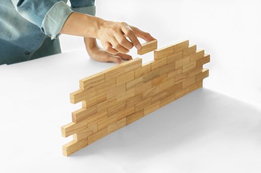 Woman in jeans shirt holding blocks wood game Building a small brick wall Risk concept