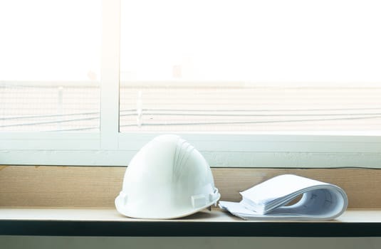 Construction drawing blueprints and white hard hat on table