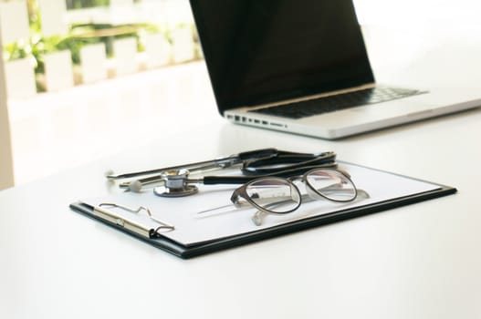 Close-up of stethoscope, paper, laptop on doctor table. selective focus