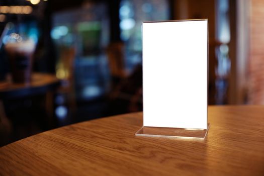 Mock up Menu frame standing on wood table in Bar restaurant cafe. space for text.