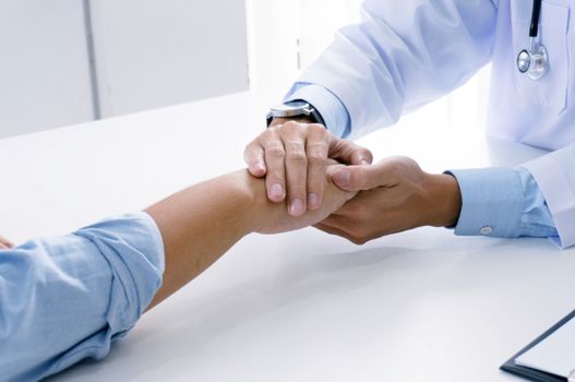 Doctor holding patient's hand, and reassuring his male patient helping hand concept