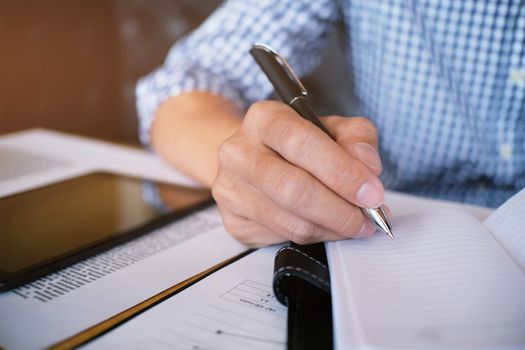 Man student writes information from portable tablet while prepare for lectures in University campus.