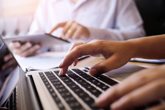 Man working by using a laptop computer on wooden table. Hands typing on a keyboard.