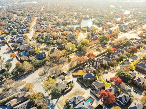 Aerial drone view lakeside residential neighborhood in North of Dallas, Texas, USA during fall season. Row of single-family houses subdivision with colorful autumn leaves