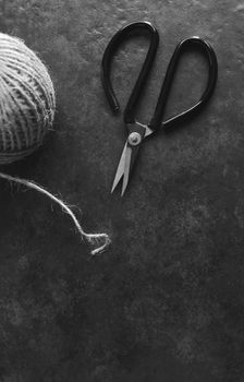 Retro florist scissors with detail of rough hessian twine on grey background with copy space - monochrome processing