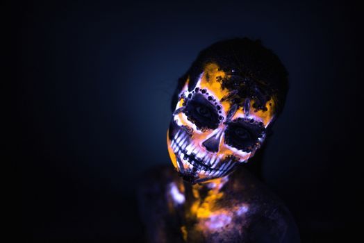 Girl's Face painted in fluorescent UV colors and looks like Neon Glowing Skull