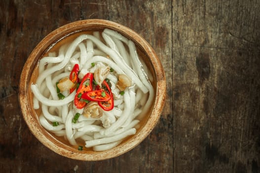 closeup of udon noodle in wood bowl on wooden floor background