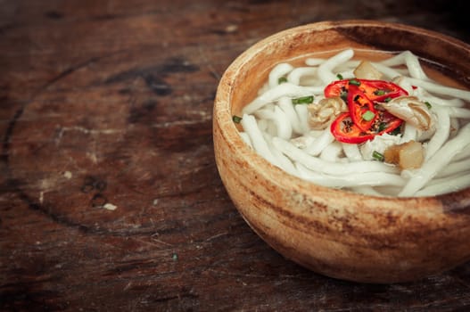 closeup of udon noodle in wood bowl on wooden floor background