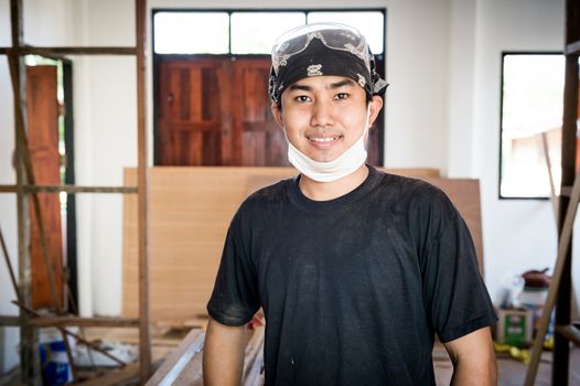 Young male carpenter portrait in workshop interior