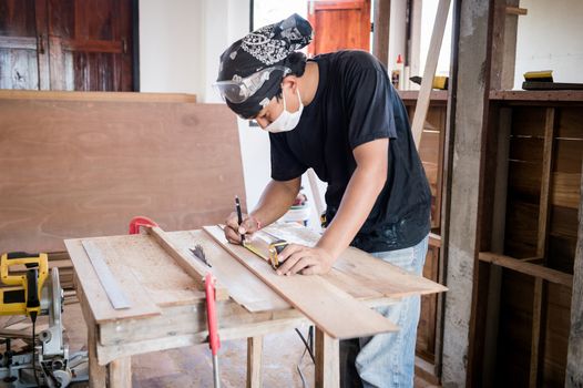 Young male carpenter working with wood in workshop