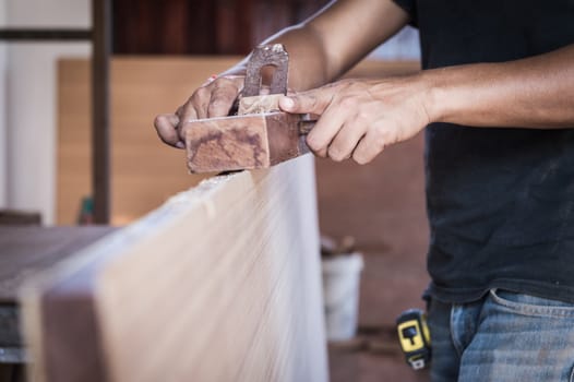 closeup of a hand take a planer tool with wood