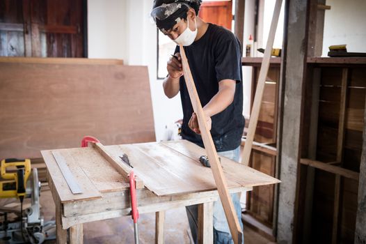 Young male carpenter working with wood in workshop