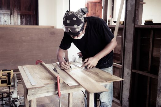 Young male carpenter working with wood in workshop