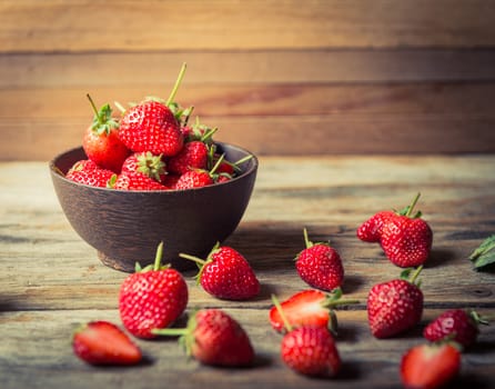 closeup of strawberry fruit in wood cup on grunge wooden background