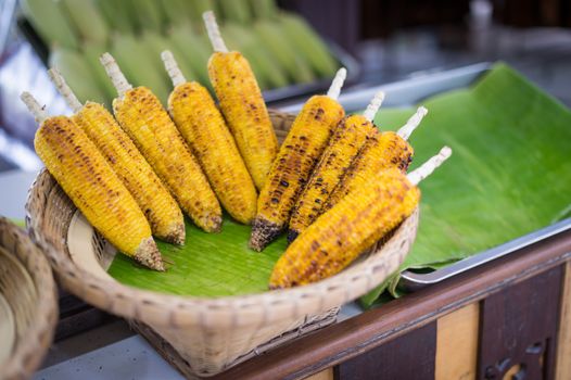 closeup of grilled corn in wood basket, food stylish of asian culture.