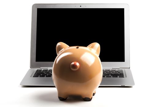 Piggy Bank In Front of Silver Laptop with Blank Black Screen, Isolated on White Background