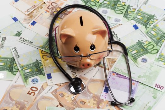 Piggy Bank With Black Stethoscope on Euro Banknotes . European Health Insurance Costs