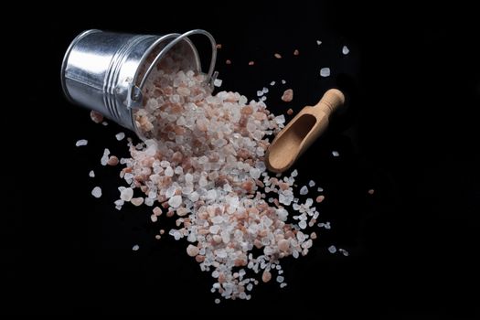 Silver Color Metal Bucket With Spilled Himalayan Salt and Wood Spice Scoop on Black Background