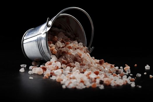 Himalayan Salt Spilled From Metal Silver Bucket on Black Background