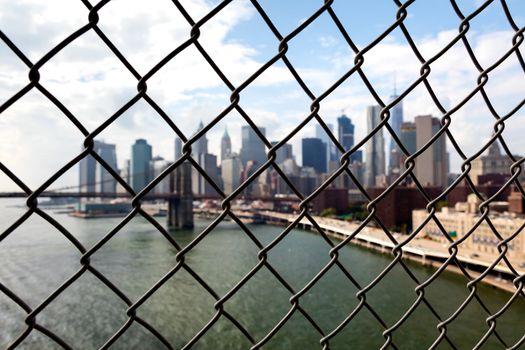 Brooklyn Bridge in New York with Manhattan through the wired mesh