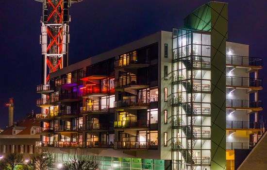 Dutch architecture by night, lighted apartments building with staircase and balconies