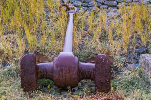 rusty and old big pirate ship anchor laying on the ground, sailor decoration, background