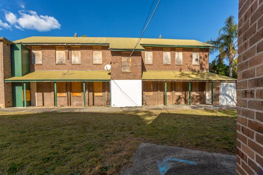 Abandoned building of the old Peat Island Asylum, now falling into disrepair, roof guttering and drainage pipes broken .  The windows are all boarded up