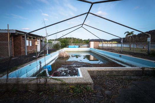 Abandoned forgotton swimming pool of the Peat Island asylum, now growing reeds and thorny thistles. Taken at dusk, in the distance is the M1 bridge. 