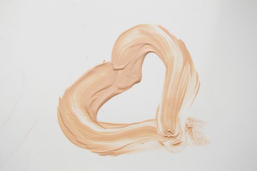 Painted heart, a smear of liquid type Foundation, concealer, white background.