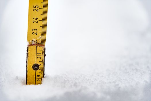 Yellow meter rule is stuck in a snow in winter in Bavaria, Germany