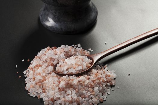 Pink Himalayan Salt Pile With Brown Wood Spoon and Mortar Close-up