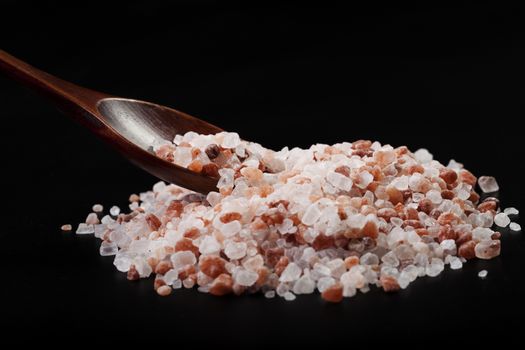 Brown Wood Spoon in Himalayan Salt Pile On Black Background