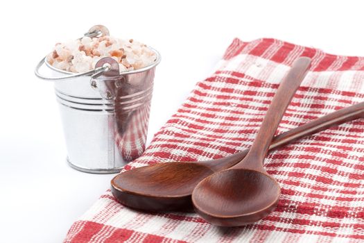 Himalayan Salt Raw Crystals Pile in Silver Metal Bucket and Two Wood Spons Isolated on White Background