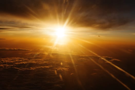 Sunrise over fluffy clouds with bright rays of light