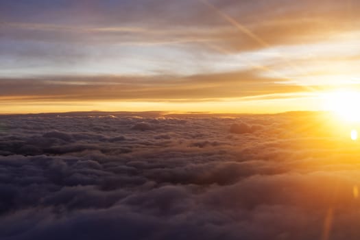 Sunrise over fluffy clouds with bright rays of light