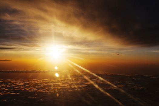 Sunrise over fluffy clouds with bright rays of light