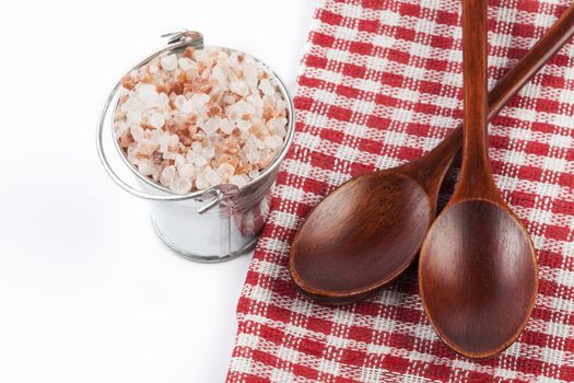 Himalayan Salt Raw Crystals Pile in Silver Metal Bucket and Two Wood Spons Isolated on White Background