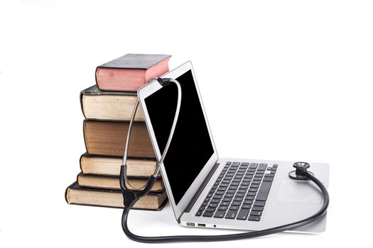 Silver laptop with black stethoscope and old books pile isolated on white background