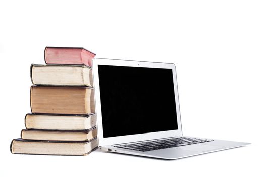 Isolated silver laptop with pile of old books