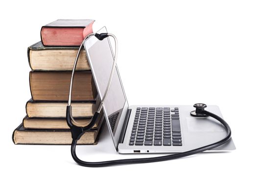 Silver laptop with black stethoscope and old books pile isolated on white background