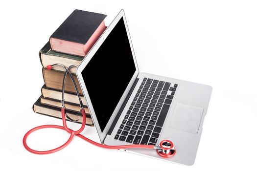 Silver laptop with red stethoscope and old books pile isolated on white background