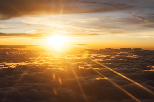 Sunrise over fluffy clouds with bright rays of light