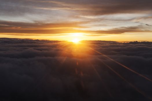 Sunrise over fluffy clouds with bright rays of light